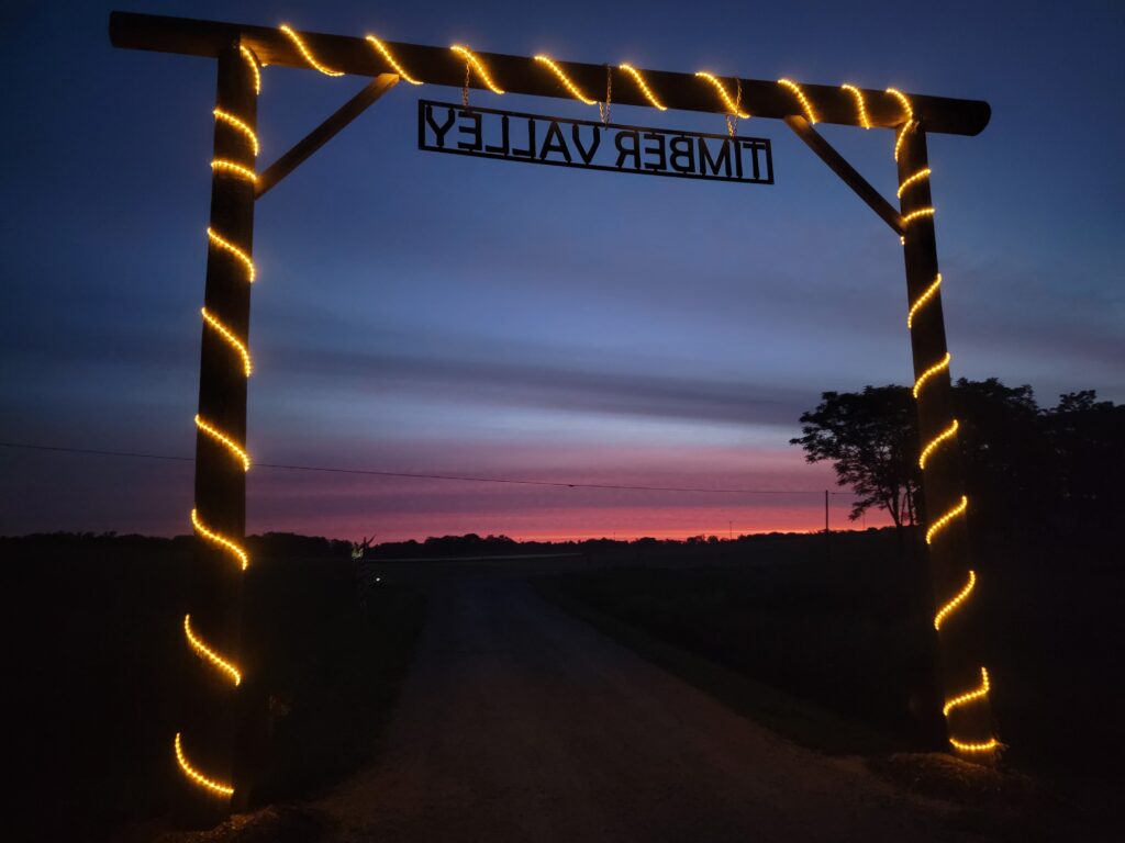 Chasing the Golden Hour Glow 🌅
The most important rule for a scenic Maryland driveway entrance photo is lighting. Aim for the "Golden Hour"—the hour just before sunset—when the light turns soft and warm. This timing is perfect for Timber Valley Retreat landmark photography, as it highlights the natural texture of the wood and the depth of the 100-acre forest behind the arch. It creates a professional-looking glow that makes your family portraits truly stand out.