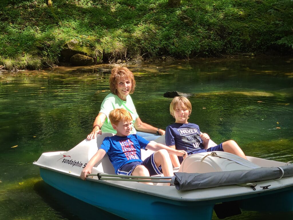 Family enjoying quality time together on the Spring-Fed Pond at Timber Valley Retreat in a paddle boat surrounded by peaceful nature.