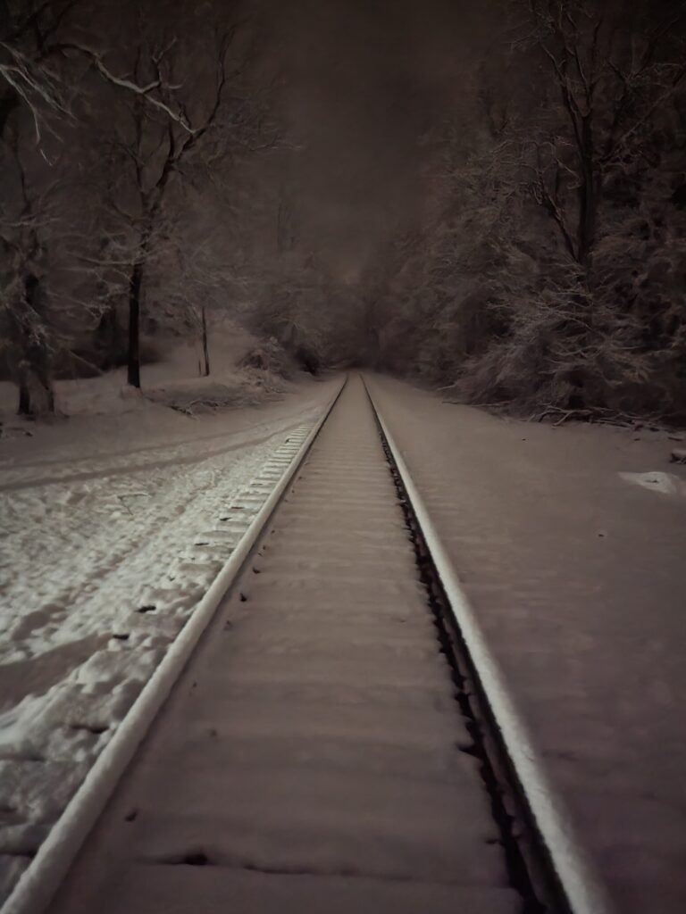 Snow-covered railroad beneath a peaceful winter night sky near Timber Valley Retreat, a Maryland Dark Sky Cabin in Western Maryland.