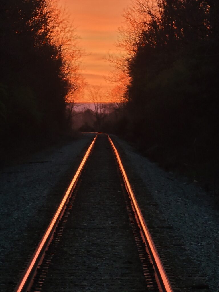Golden sunrise reflecting along railroad tracks near Timber Valley Retreat in Western Maryland, symbolizing hope and new beginnings.