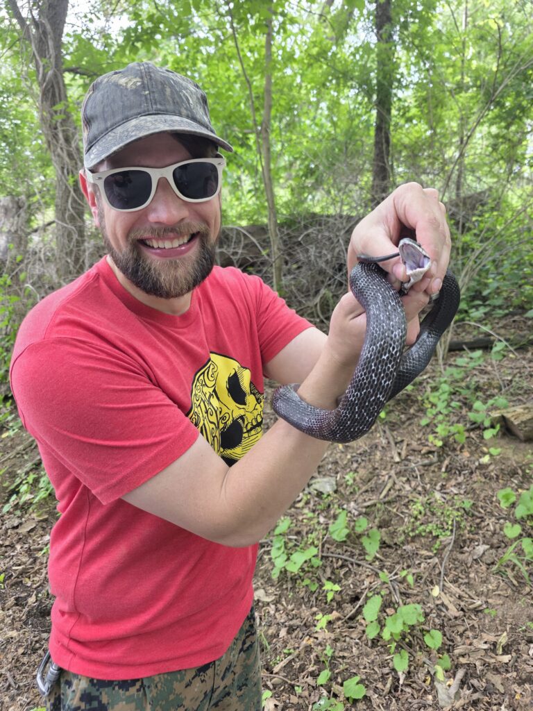 A Timber Valley Retreat guest holds a non-venomous black rat snake after Tom safely removed it from a country road during a Timber Valley Trailblazer wagon ride.