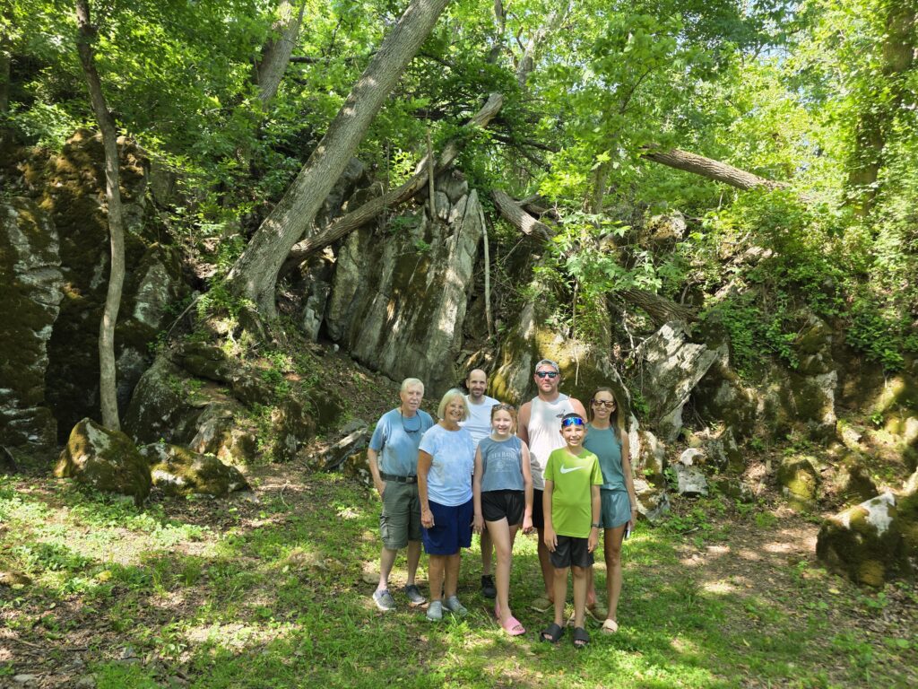 Family celebrating a 75th birthday among the moss-covered boulders at Timber Valley Retreat during a Relaxing Nature Cabin Western Maryland getaway.