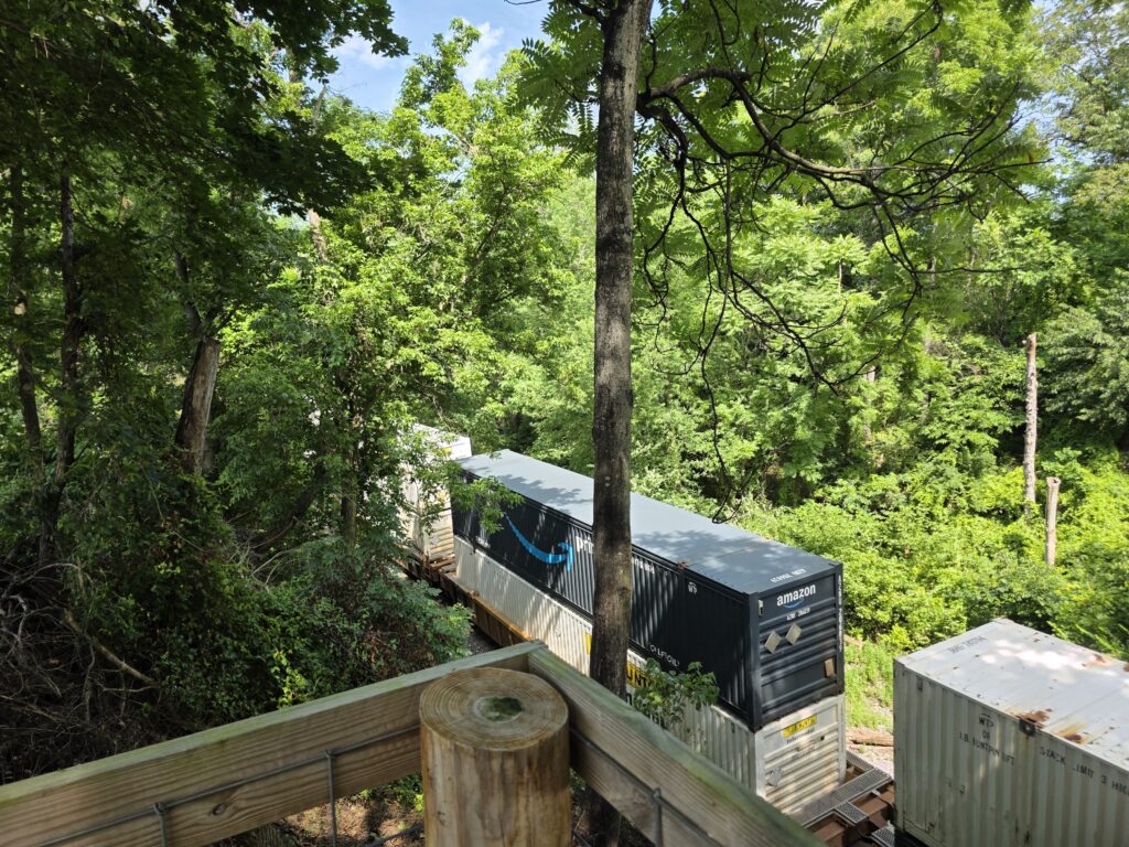 CSX freight train traveling through the wooded valley near Timber Valley Retreat with nearby railroad museums and attractions in Western Maryland.