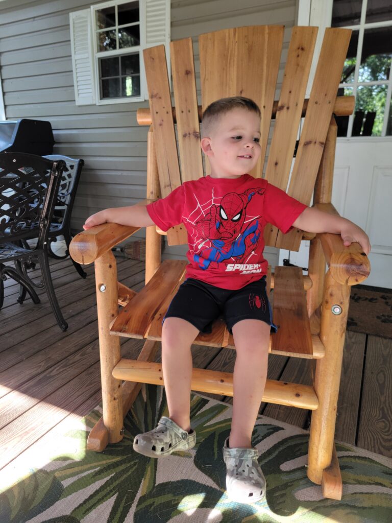 Child enjoying Multi-Generational Family Vacations while relaxing in a wooden rocking chair on the porch at Timber Valley Retreat during a Family Getaway Western Maryland.