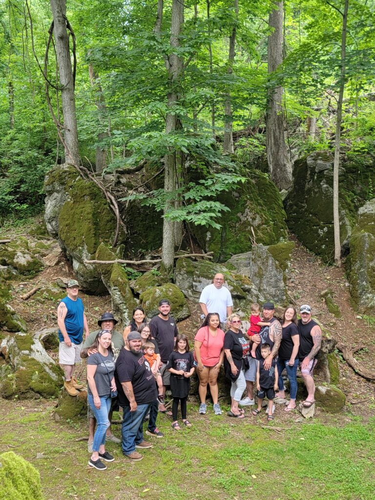 Large family group gathered among moss-covered boulders in the woodland at Timber Valley Retreat in Clear Spring Maryland during a group nature getaway.