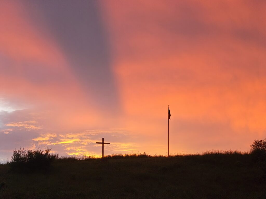 The Cross on the Hill silhouetted against a colorful sunset at Timber Valley Retreat, an Exclusive Private Cabin Retreat in Washington County, Maryland near Washington DC, Northern Virginia, Pennsylvania, West Virginia, and Maryland's Eastern Shore.