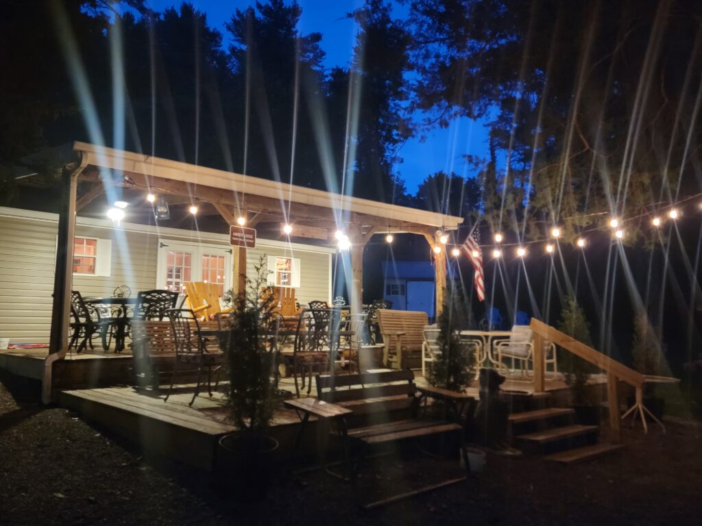 Evening reflections at Timber Valley Retreat featuring a warmly lit cabin porch with string lights at an Exclusive Private Cabin Retreat in Washington County, Maryland.