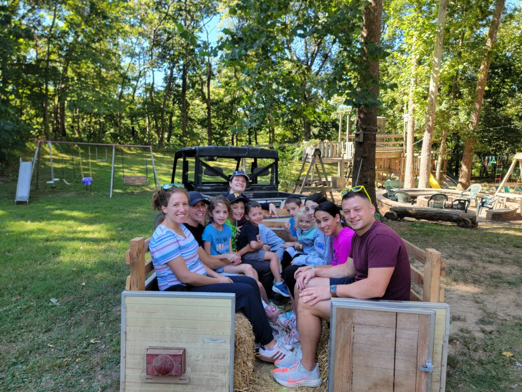 Family group enjoying a wagon ride together at Timber Valley Retreat in Clear Spring Maryland surrounded by trees and outdoor recreation.