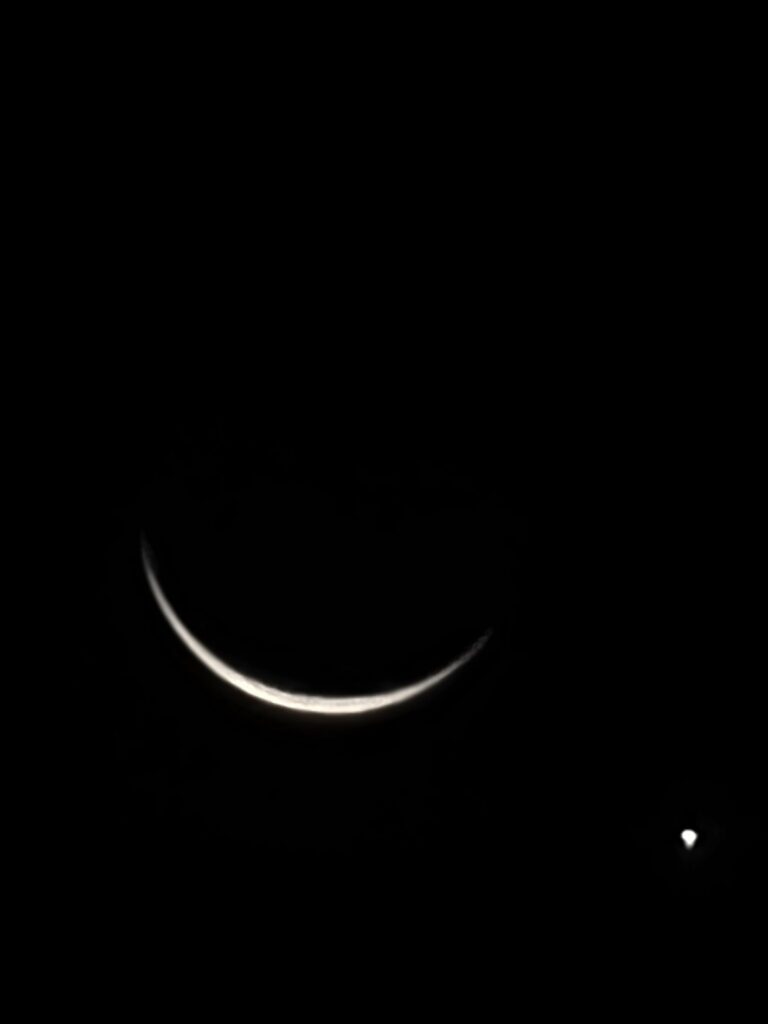 Crescent moon with a bright celestial object shining nearby in the dark night sky at Timber Valley Retreat