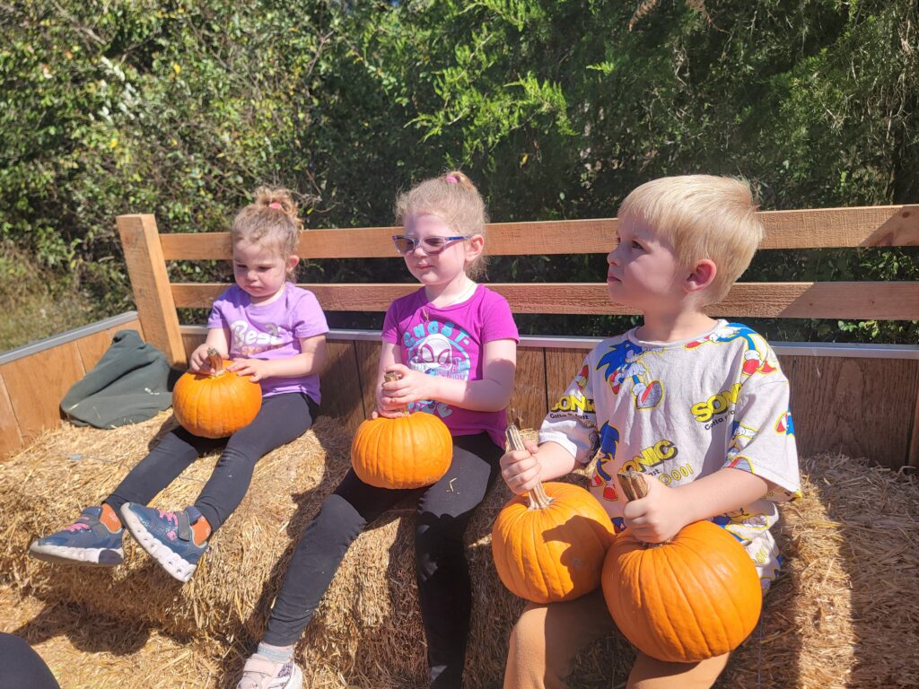 Fall Glamping Maryland with children enjoying pumpkins during a hay ride at Timber Valley Retreat