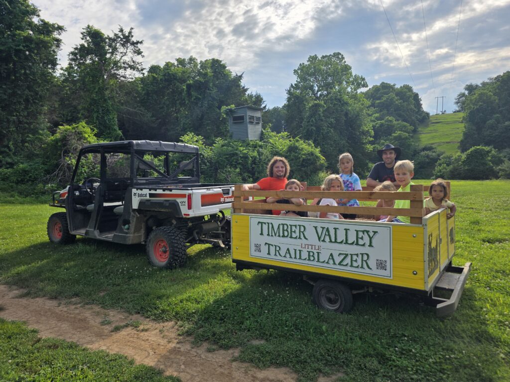 Family enjoying a ride on the Little Trailblazer wagon at Timber Valley Retreat in Western Maryland.