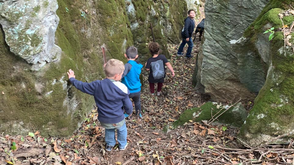 Children exploring between moss-covered boulders in the woodland at Timber Valley Retreat in Clear Spring Maryland.