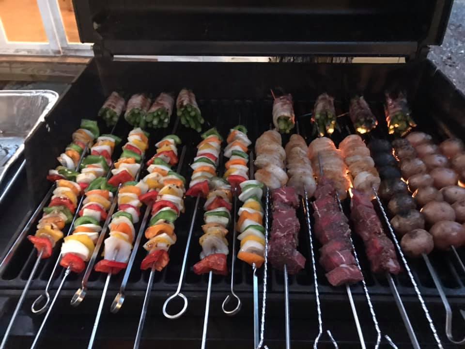 Family group preparing a meal together on an outdoor grill at Timber Valley Retreat in Clear Spring Maryland during a group getaway.