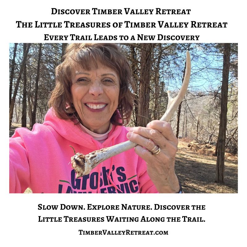 Karen smiles while holding a naturally shed deer antler along a wooded trail at Timber Valley Retreat in Western Maryland, celebrating the little treasures guests can discover while exploring nature.
