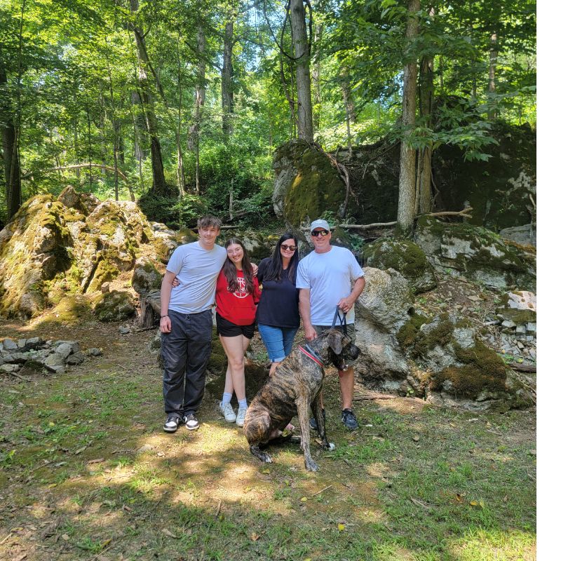 Family Time Unplugged Maryland. Family spending time together with their dog among moss-covered boulders in the woodland at Timber Valley Retreat in Clear Spring Maryland.