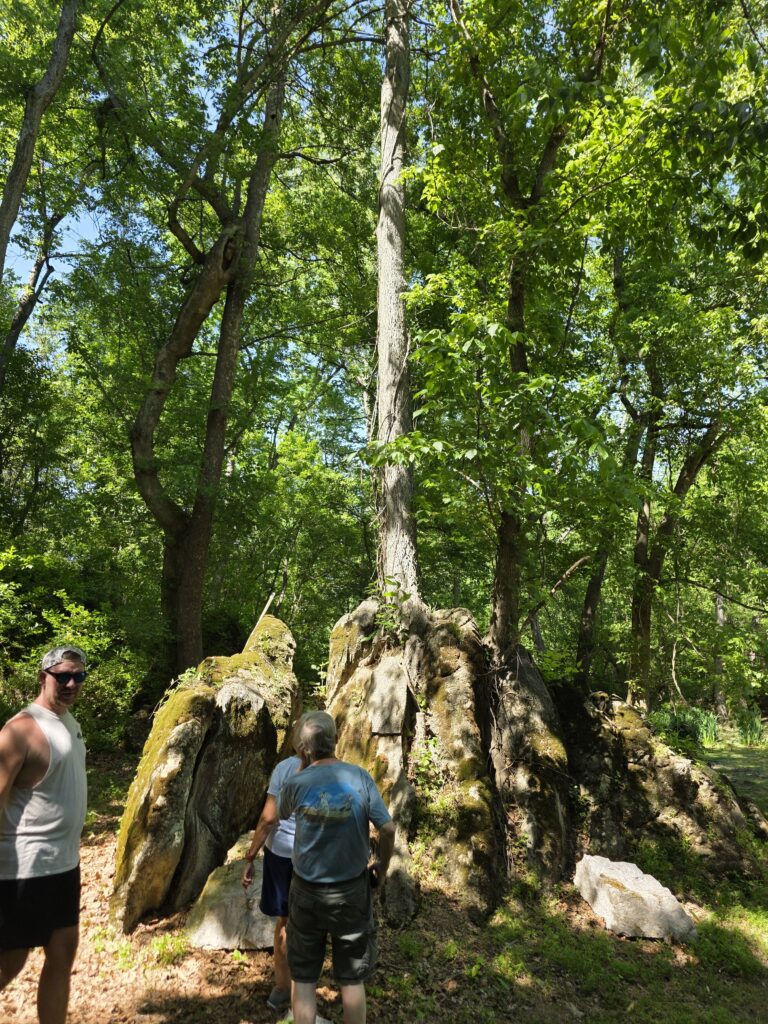 Guests listening to Tom talk about the Tree-Mendous Tree among moss-covered rocks and woodland at Timber Valley Retreat in Clear Spring Maryland.
