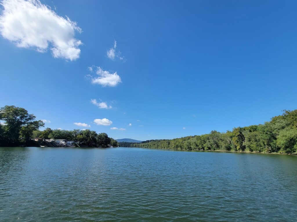The Potomac River near Timber Valley Retreat on a sunny summer day with blue skies, calm water, wooded shoreline and distant hills.
